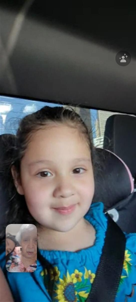 Young girl looks happy sitting in her car seat, enjoying a joyful family outing on a sunny day.