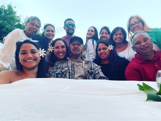 A joyful gathering of friends with flowers in their hair enjoying each other's company in a park.