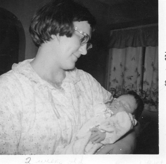 A woman lovingly holds a newborn baby in a cozy and intimate family setting.