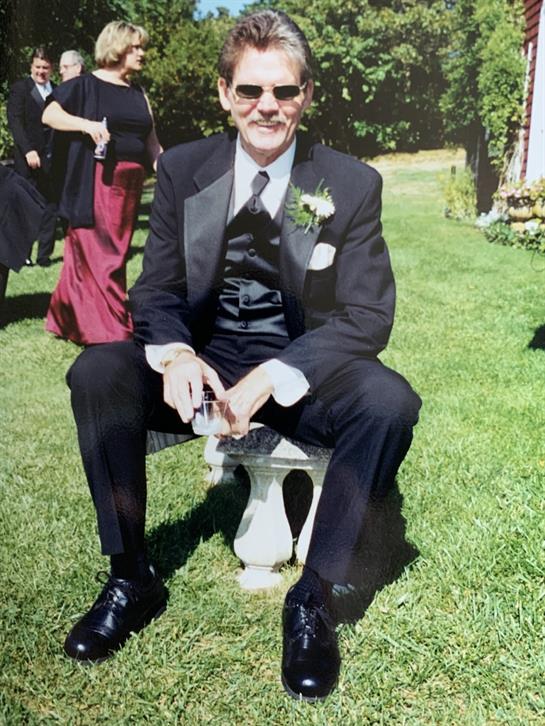 A man in a tuxedo sitting on a bench