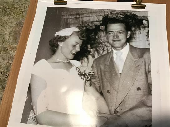 A newlywed couple smiles joyfully, surrounded by flowers in a classic celebration.