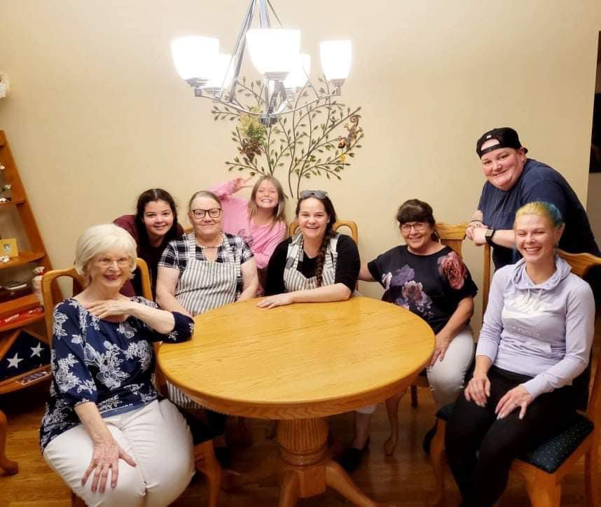 Friends are enjoying a joyful gathering at a wooden table in a warm, inviting room.