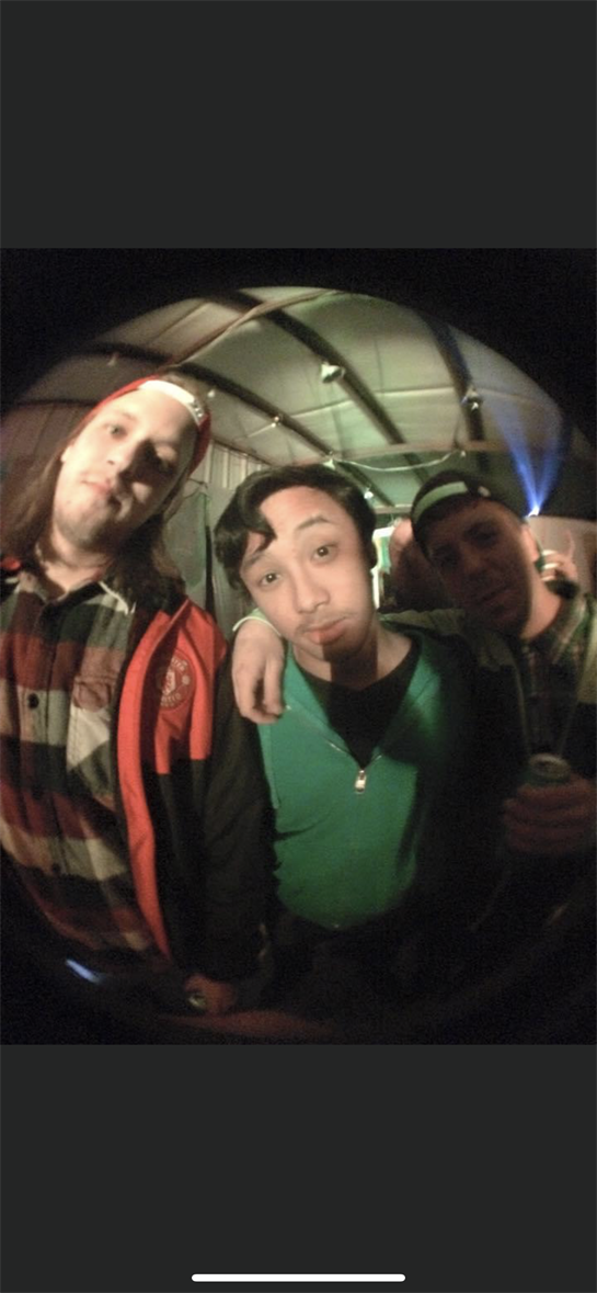 Three friends pose together, showcasing their casual outfits in a lively indoor setting.