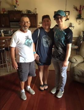 Three family members pose together in a cheerful indoor atmosphere, smiling happily.
