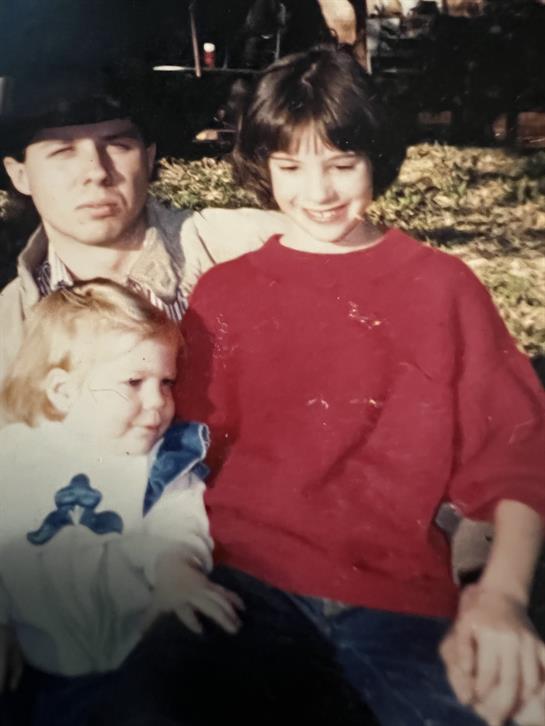 Two children and an adult enjoy a sunny day in the park, sharing smiles and laughter together.