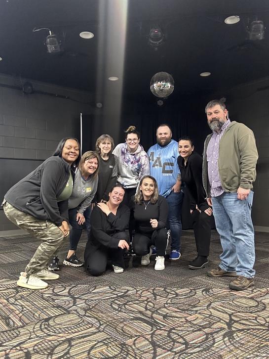 Friends gather, smiling and enjoying a lively event at an indoor venue.
