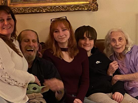 Five family members enjoy quality time together, laughing and sharing stories in a warm atmosphere.
