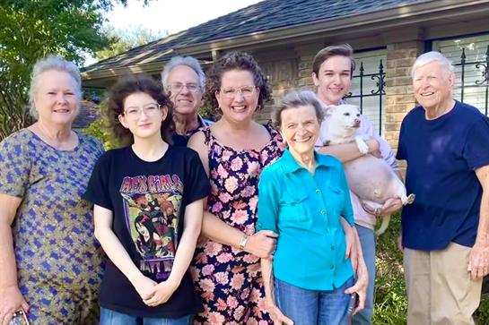 Family members happily gather in a backyard, showcasing joy and togetherness with a pet.