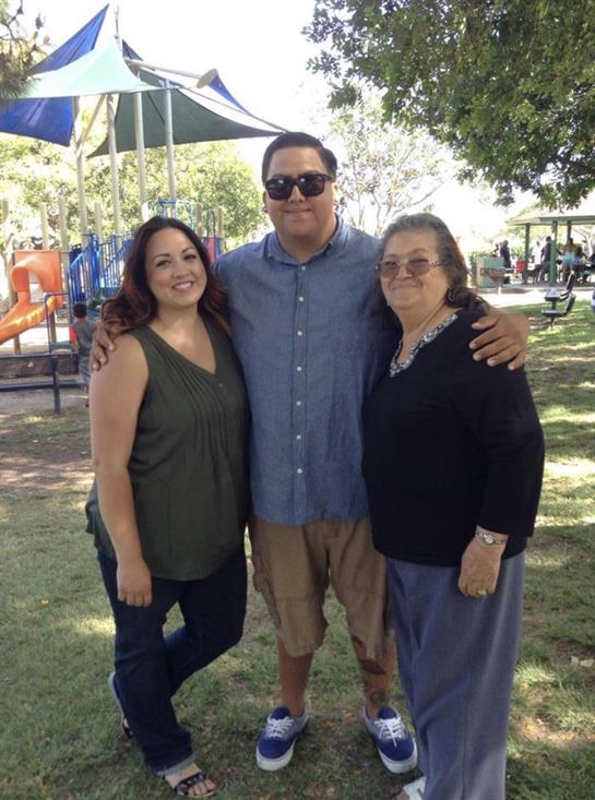 Three family members pose happily in a park on a sunny, laughter-filled afternoon.