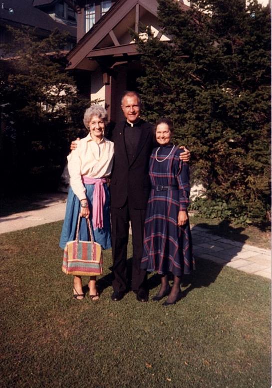 Three people smile warmly together in a garden, enjoying each other's company.