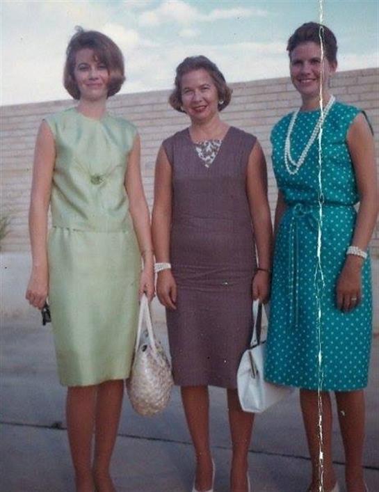 Three women dressed in stylish outfits pose together, showcasing their fashion sense and joy.