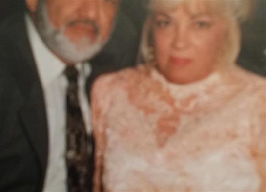A couple dressed elegantly engages in a joyful moment at a celebration indoors.