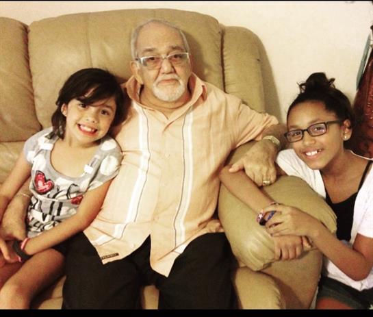 A grandfather shares laughter and love with his two granddaughters in a cozy living room setting.
