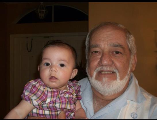 A joyful grandfather is cradling his grandchild, both sharing a moment of love in their home.