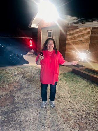 A woman holding a phone and sparklers