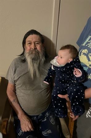 A man with long beard holding a baby