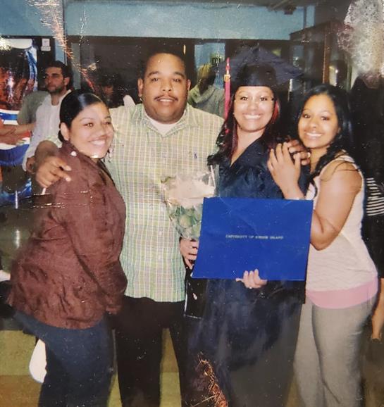 Group of four people joyfully celebrating a graduation with smiles and flowers in hand.