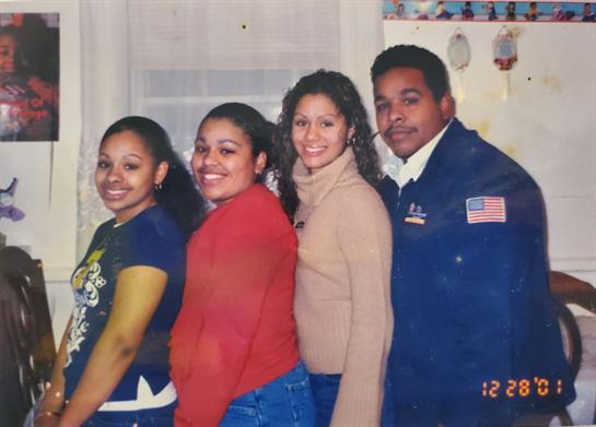 Four people smile in a cozy kitchen, enjoying camaraderie at a family event.