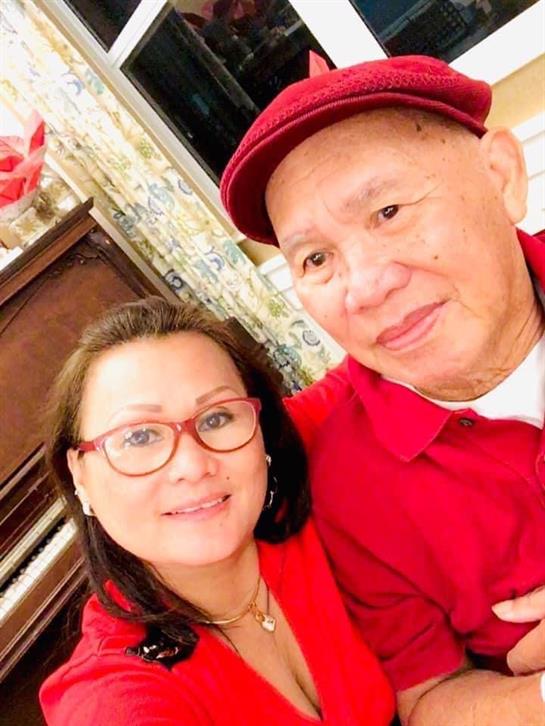 Happy couple takes a selfie while dressed in matching red outfits and smiling warmly.