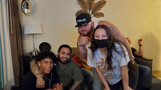 Friends gather in a living room, laughing and enjoying their time together while wearing masks.