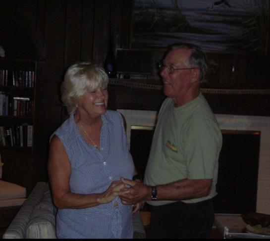 A couple shares a joyful dance in a cozy cabin, surrounded by warm lighting and a rustic atmosphere.
