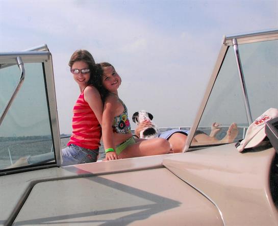 Friends relax on a boat with their dog, sharing laughter and summer fun under the sun.