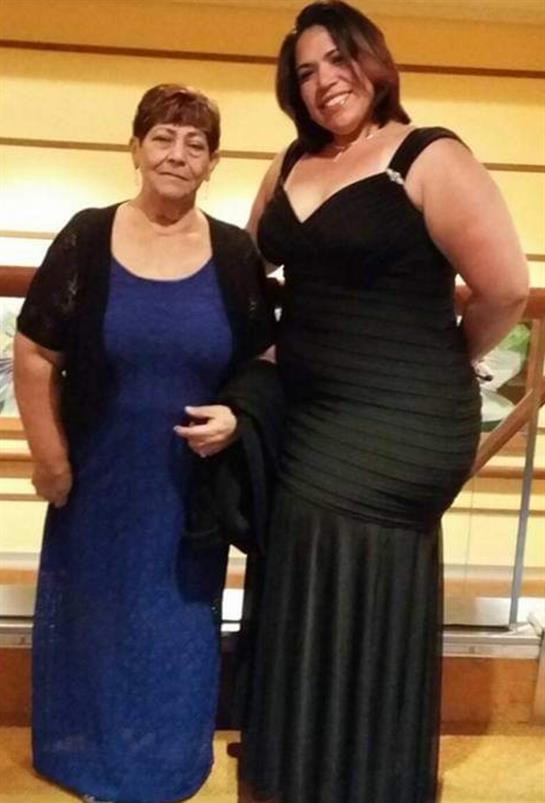 Two women pose together, showcasing their stylish evening gowns in a vibrant location.