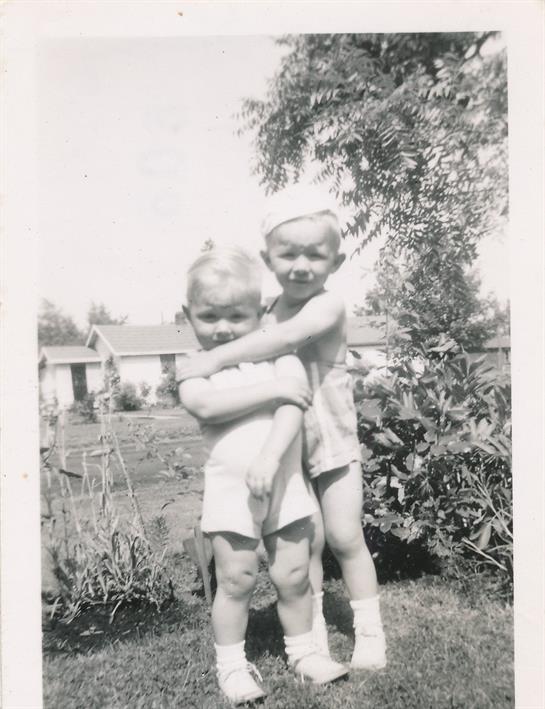 A black and white photo of a couple of children hugging