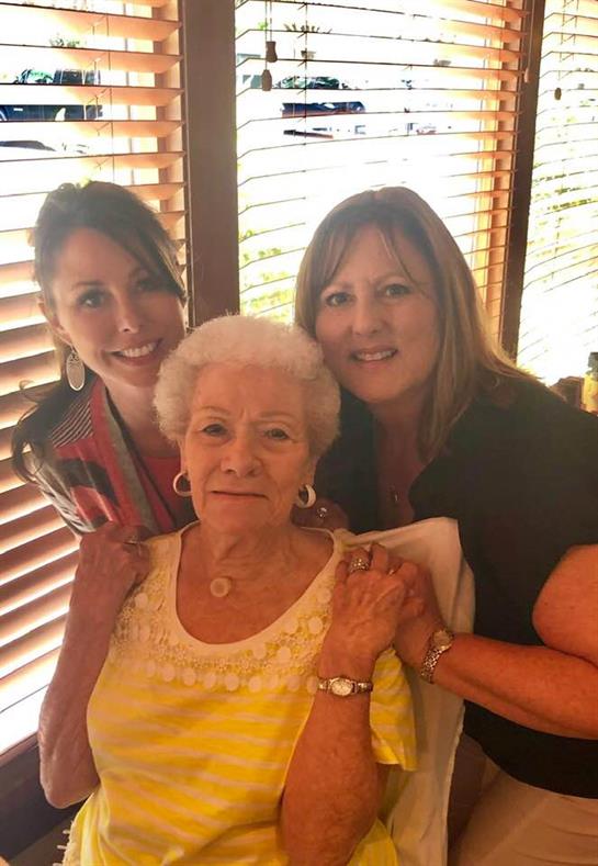 Three women enjoying time together at a restaurant, sharing smiles and affection for one another.
