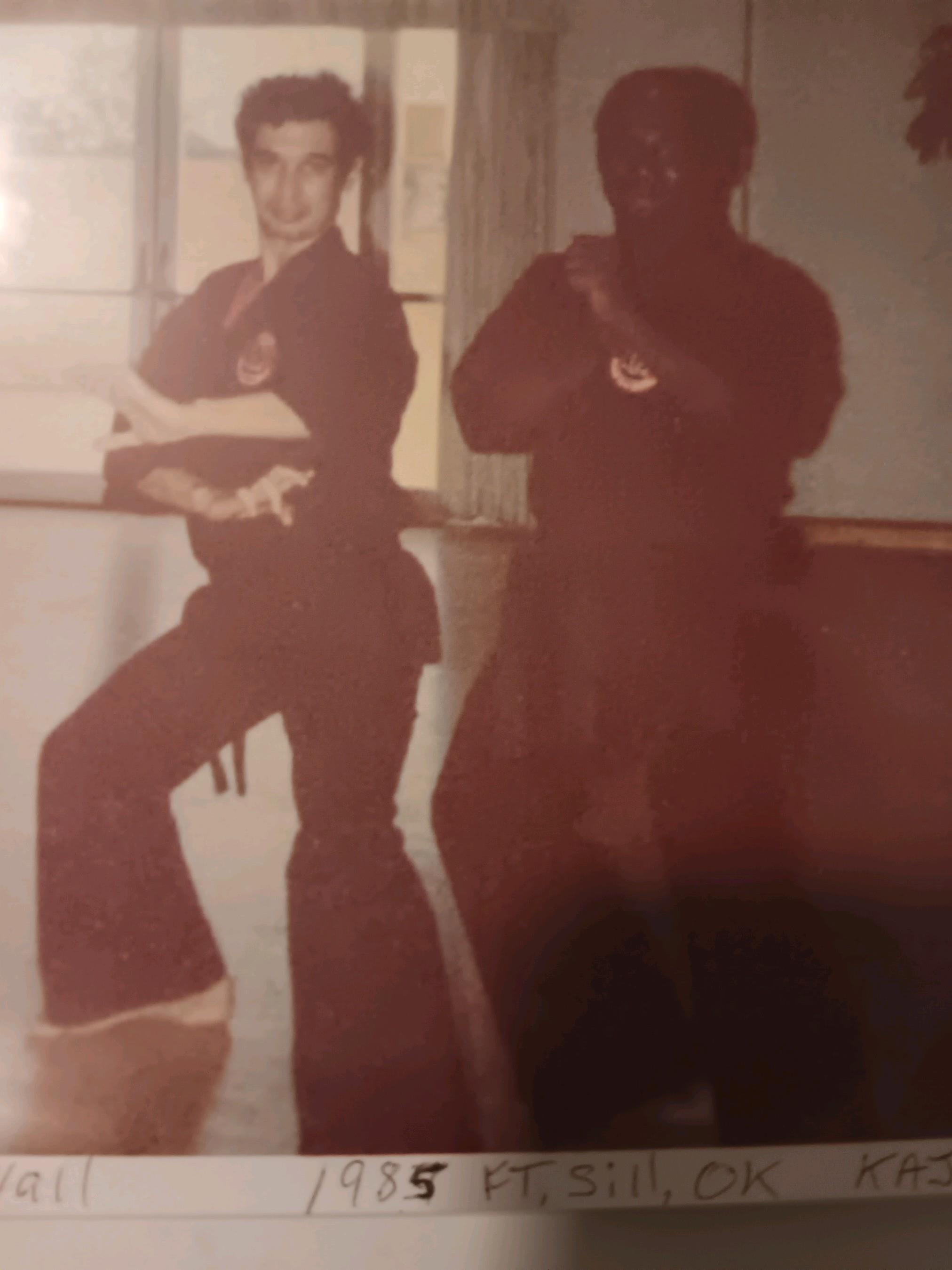 Two martial arts practitioners pose in a training studio, showcasing traditional moves in 1985.