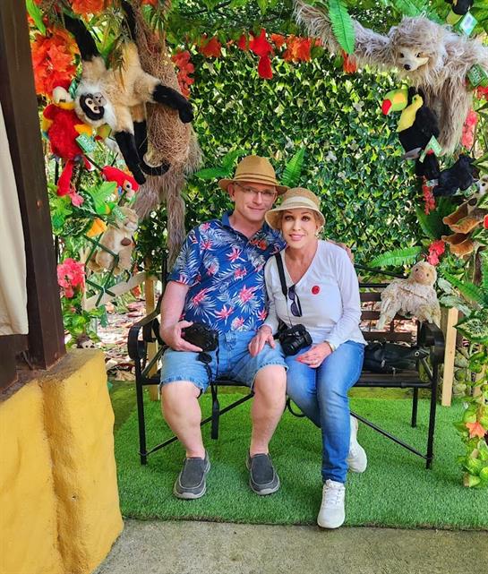 Lively decorations frame a couple sharing a joyful moment outdoors in a tropical garden.