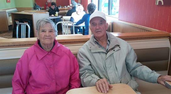 An elderly couple sits at a table in a cozy restaurant enjoying their time together and lunch.