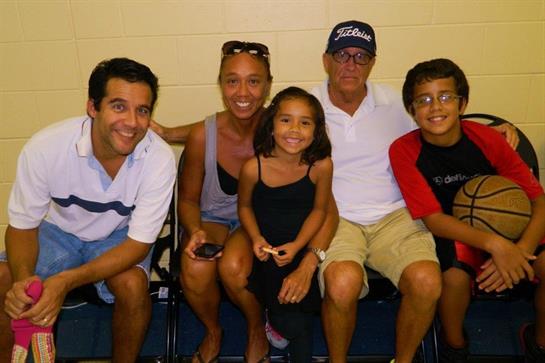 A joyful family sits together, smiling at a community event, enjoying quality time during summer.