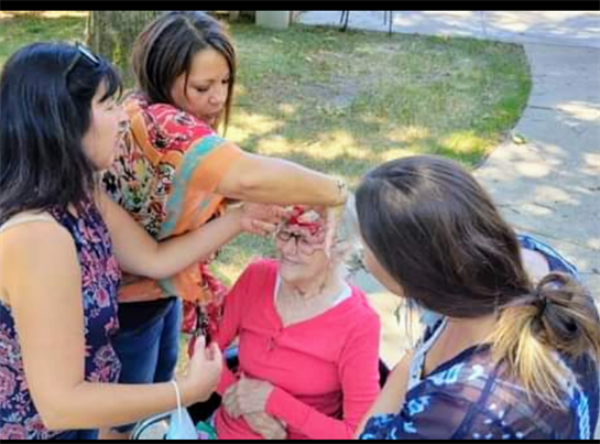A group of women standing around an old woman