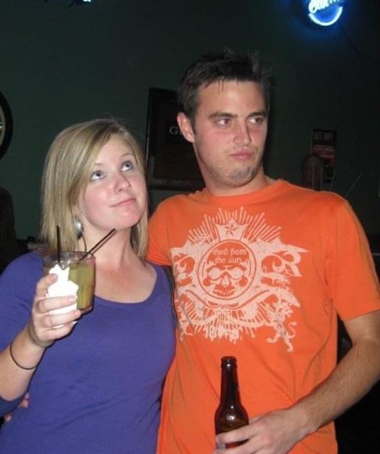 Two friends pose together with drinks in hand, smiling playfully at the camera.
