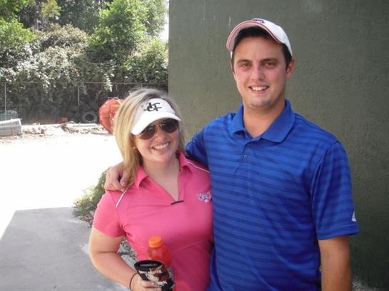 Two friends pose together at a golf course, both smiling and dressed casually for summer.