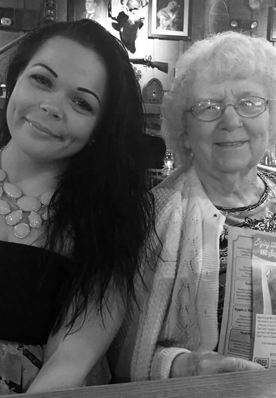 Two women smile warmly, enjoying each other's company during a family celebration at a restaurant.