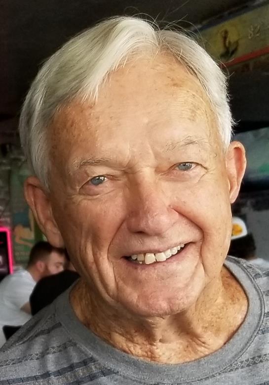 A cheerful elderly man enjoys a joyful moment with friends in a busy cafe atmosphere.