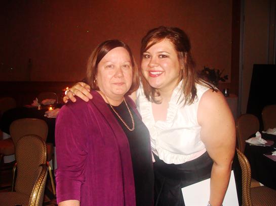 Smiling women pose in elegant attire at a celebratory gathering, creating a joyful atmosphere.