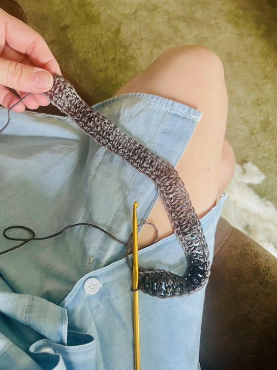 A person knitting a piece of yarn