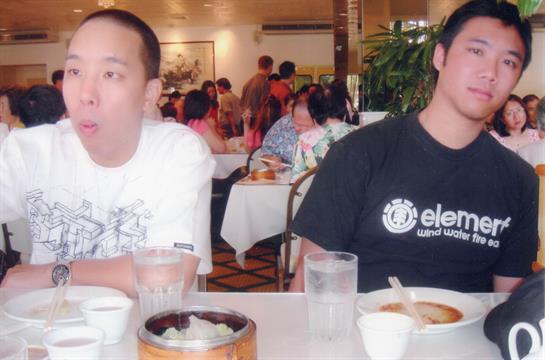 Friends share a meal in a crowded restaurant, surrounded by diners and vibrant atmosphere.