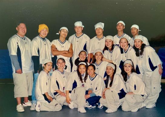 Dance group gathers in a studio, displaying teamwork and excitement before a performance.