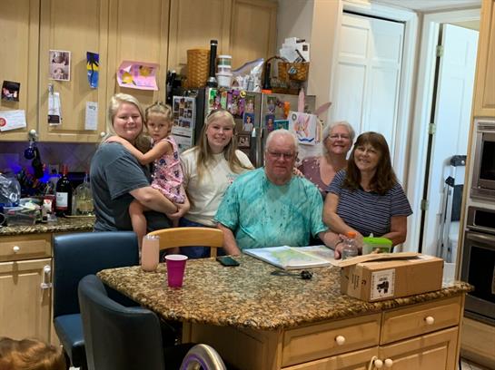 Family members gather around a kitchen island, enjoying each other's company and sharing smiles.