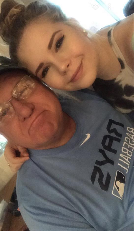 Granddaughter embraces her grandfather with a smile during a family celebration indoors.