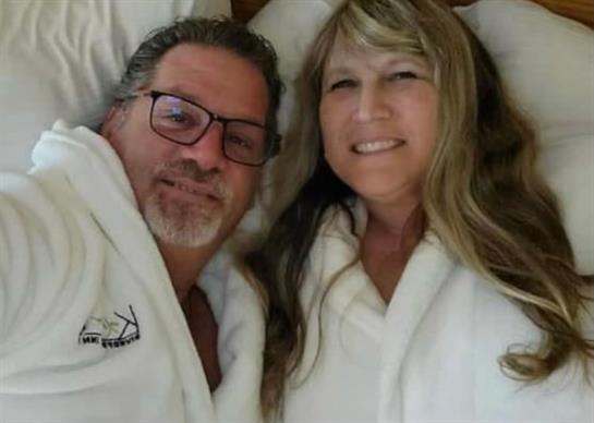A couple smiles happily while relaxing together in bathrobes, creating a warm atmosphere.