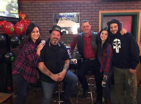 Five friends strike a lively pose at a bar, showcasing their casual style and camaraderie.