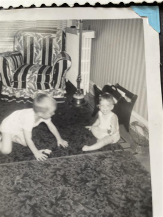 A black and white photo of a couple of children playing on a rug