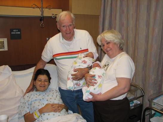 Joyful family visits a new mother in a hospital room, celebrating the birth of twins.