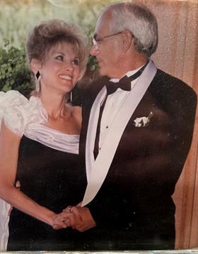 A dressed-up couple shares a joyful moment together at a formal gathering, smiling and connecting.
