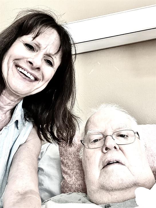 Two seniors share a moment of joy, smiling together in a warm, inviting room filled with light.